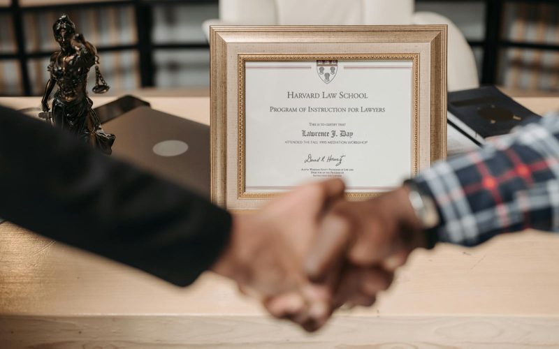 Harvard Law School degree with handshake representing achievement and professional agreement.