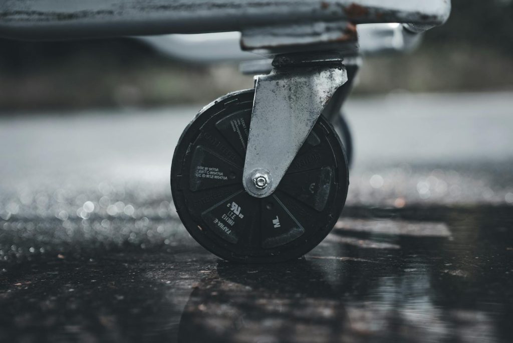 Close-up photo of a metal caster wheel on a wet surface, showcasing industrial design.