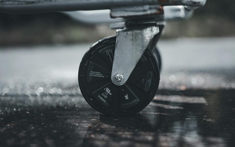 Close-up photo of a metal caster wheel on a wet surface, showcasing industrial design.