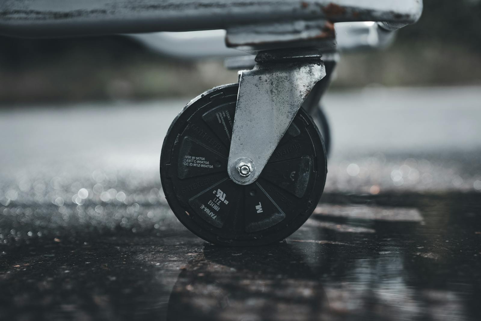 Close-up photo of a metal caster wheel on a wet surface, showcasing industrial design.